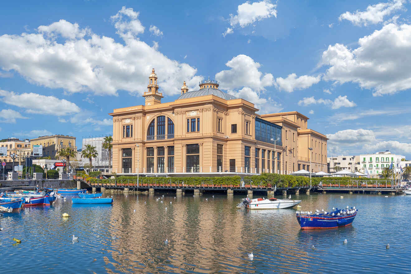 Elegant historical building by a harbor with blue boats and clear blue sky in Bari, Italy.